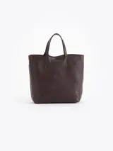 Cartera tipo tote bag pequeña de cuero vacuno negro con diseño de abejas grabadas en bajo relieve. Cuenta con doble asa de mano, correa ajustable y un tag colgante con dije metálico en forma de abeja.