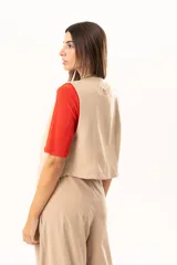Chaleco de corte sastre en color beige, con escote en V, cierre frontal mediante botones y costuras decorativas en contraste.
