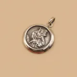 Medalla circular de plata 925 con relieve de San Cristóbal cargando al niño Jesús, con acabado pulido en los bordes y oxidado en el centro.