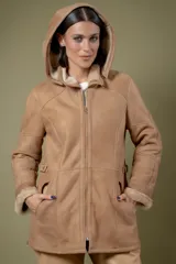 Campera de babylamb color beige con interior de piel sintética al tono. Presenta cierre frontal, capucha desmontable, bolsillos laterales, presillas ajustables en la cintura y cierres en los laterales del ruedo.