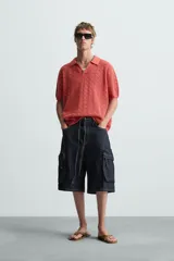 Polo color ladrillo de punto calado con cuello solapa y abertura frontal.