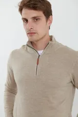 Sweater verde oliva de tejido acrílico con textura similar al cashmere, corte clásico, cuello alto con cierre metálico y tirador de cuerina ecológica.