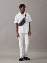 Riñonera Calvin Klein Jeans color gris oscuro con logo estampado en el frente, correa ajustable con hebilla y cierre superior con cremallera.