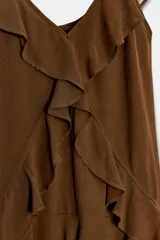 Vestido corto color marrón con escote en pico y tirantes anchos. Presenta un diseño con múltiples volantes en cascada que recorren el frente y el bajo, con un acabado asimétrico y forro interior a tono.