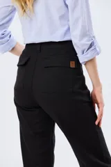 Pantalón de gabardina marrón, de corte recto con pinza en el bajo y detalles de botones en los tobillos.