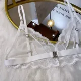 Set de lencería de cuatro piezas compuesto por bralette de encaje y microtul, tanga regulable, portaligas y ligas. Diseño con transparencias y detalles de encaje.
