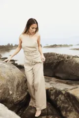 Pantalón de lino color beige, de calce amplio y tiro alto, con aberturas laterales en el ruedo.