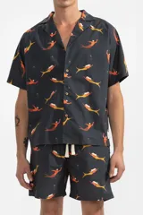 Short de baño negro con estampado de sirenas color naranja y amarillo. Tiene cintura elástica con cordón ajustable y bolsillos laterales.