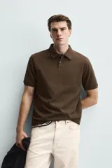 Polo de corte regular fit en tejido de algodón con estructura vertical color beige. Presenta cuello solapa, cierre frontal de botonadura y manga corta con rib.