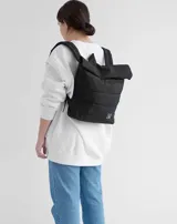 Mochila negra acolchada con cierre superior enrollable y logo rectangular en la parte inferior.