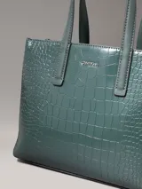 Cartera tote verde con textura de piel de cocodrilo, doble asa de mano y correa bandolera desmontable.