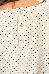 Blusa cruda con estampado de lunares negros, de manga corta y cuello redondo.