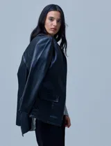 Blazer de eco cuero negro con corte oversized, cuello con solapa, cierre frontal con botones y bolsillos delanteros aplicados.