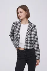 Blazer corto de poliéster con diseño a cuadros en blanco y negro, cuello solapa y cierre frontal de doble botonadura.