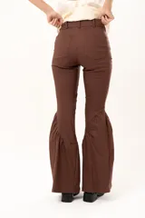 Pantalón de corte ajustado en la parte superior y pierna acampanada con volados en el ruedo. Presenta cierre frontal y bolsillos laterales.