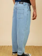 Jean de corte baggy fit en denim color azul claro, con diseño de cinco bolsillos y cierre frontal con botón metálico.