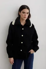 Camisa de paño de lana, color negro, con cuello tejido en contraste y cierre frontal de botones claros. Presenta bolsillos frontales y diseño de corte recto.