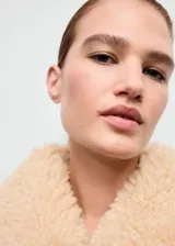 Chaqueta de efecto ante color marrón con forro y cuello de borreguito en tono crema. Presenta cierre frontal con cremallera, diseño recto y dos bolsillos laterales.