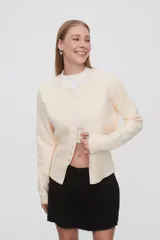 Saco color crema, de corte ajustado, con cuello redondo a la base y cierre frontal con botones.