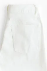 Jean de corte recto confeccionado en denim de algodón blanco, con bolsillos laterales y detalles de broderie en los laterales de las piernas y en el bajo.