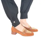 Mocasín de cuero combinado con gamuza en tonos café y tostado, con taco ancho y punta redondeada.