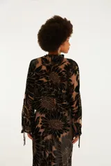 Blusa de manga larga con escote en V, cierre frontal con lazos ajustables y terminaciones de volados en cuello y puños. Confeccionada en tejido semitransparente con diseño floral aterciopelado.