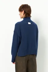 Polera de tejido de punto color bordó, con cuello alto, manga larga y costura vertical central en el frente.