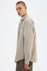 Camisa de popelina de algodón con cuello inglés, tapeta clásica y bolsillo superior abierto. Presenta un canesú en la espalda y mangas largas con puños abotonados. El bajo es levemente redondeado.