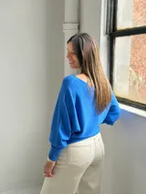 Sweater de punto color azul vibrante, con diseño de textura acanalada vertical en el frente, cuello redondo y mangas murciélago con puños ajustados.