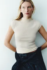 Top entallado de punto fino en color beige, con cuello alto, mangas japonesas y bajo recto.