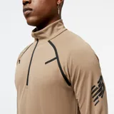 Buzo deportivo color marrón claro con cierre de cremallera corto en el cuello y detalles en negro en hombros y mangas. Logo de New Balance estampado en la manga izquierda.