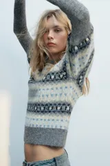 Jersey de punto con cuello redondo y mangas largas abullonadas, con diseño de jacquard geométrico en tonos grises, blancos y celestes.