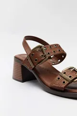 Sandalias de taco cuadrado en color whisky, con tiras decoradas con tachas y hebillas metálicas en tono bronce, y tira ajustable en el talón.