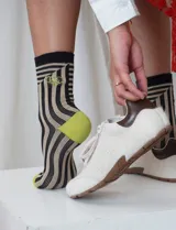 Medias de caña media con estampado de líneas onduladas en tonos beige y negro, talones y punteras en color verde lima y detalle de bordado en el lateral.