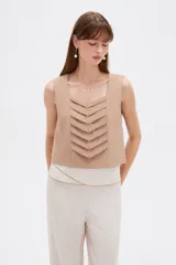 Musculosa sin mangas de color natural con cuello cuadrado y detalles de pliegues frontales en forma de chevrón.