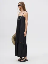 Vestido midi de denim algodón color marrón, con escote recto y tirantes finos ajustables con lazos. El corte es suelto y termina con un ruedo con semi-volado.