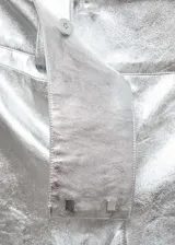 Pantalon de corte recto y tiro bajo con acabado metalizado plateado. Presenta diseño tipo cuero con cierre oculto de botón, gancho y cremallera, además de bolsillos de ribete en la parte posterior.