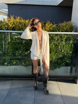 Vestido corto blanco de manga larga, con diseño cruzado, escote en V pronunciado y detalle de nudo frontal.