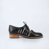 Zapato Oxford negro con cordones, capellada de cuero con textura croco y cortes calados. Taco bajo foliado y suela de goma antideslizante.