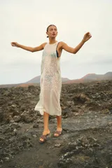 Vestido largo sin mangas, de corte amplio y confeccionado en lentejuelas color plateado.