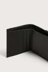 Billetera de acabado engomado en color verde oliva y negro, con compartimento para billetes, seis ranuras internas para tarjetas, dos externas y un monedero lateral con cierre de cremallera.