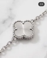 Pulsera de acero con cadena de eslabones finos y dijes colgantes en forma de flor de cuatro pétalos con textura estriada.