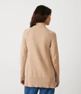 Suéter de tejido de punto color beige con cuello alto, mangas con corte raglán y puños y ruedo acanalados. Presenta un diseño clásico y cómodo con el ruedo trasero ligeramente más largo.