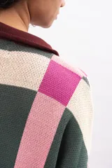 Saco largo de punto con diseño geométrico de cuadros en tonos verde, rosa y crema. Presenta cuello tipo polo, cierre frontal con botones y puños en color bordó.