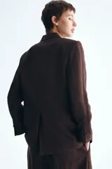 Blazer de botonadura sencilla en mezcla de lino color marrón. Modelo entallado con hombreras, solapas de pico, bolsillos delanteros ribeteados, un botón de cierre y forro interior.