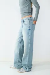 Jean de tiro alto confeccionado en denim de corte recto, con diseño clásico de cinco bolsillos y cierre frontal con cremallera y botón metálico.