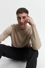 Buzo de punto color beige, con cuello redondo y mangas largas. Tejido con textura piquet y puños acanalados. Corte regular.