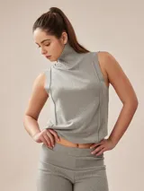 Polera sin mangas color gris melange, con cuello alto y costuras visibles en el frente.