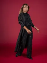 Trench negro con cuello solapa, doble botonadura y cinturón.