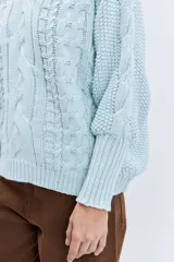 Sweater de punto en color celeste, con diseño de trenzas y textura en relieve. Presenta cuello redondo, mangas largas con puños ajustados y un corte holgado.